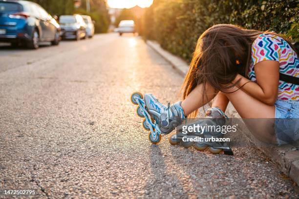 mujer joven lastimándose la rodilla después de caerse mientras patinaba sobre ruedas en el centro de la ciudad - down on one knee fotografías e imágenes de stock