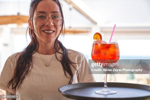 waitress looking at camera while carrying a cocktail - servir comida y bebida fotografías e imágenes de stock