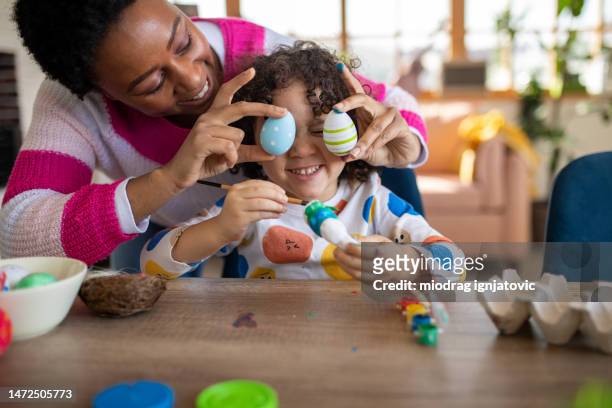 mother putting easter over her sons eyes as a joke while he paints an easter bunny - easter bunny with eggs stock pictures, royalty-free photos & images