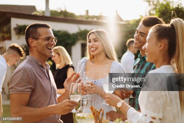 grupo de personas multirraciales disfrutando de una fiesta en el jardín en verano, bebiendo y comiendo bocadillos mientras hablan - grupo pequeño de personas fotografías e imágenes de stock