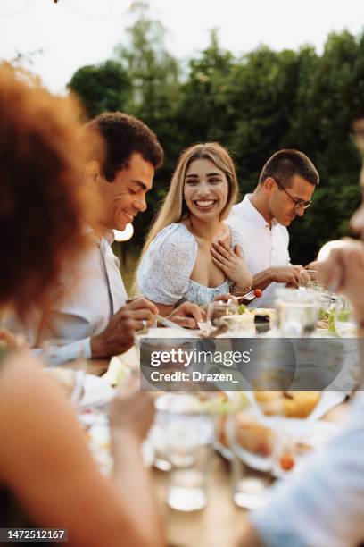 grupo multiétnico de personas que comen en el patio trasero en la noche de verano y se divierten - cena con amigos fotografías e imágenes de stock
