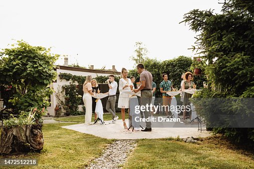 Group of multiracial people enjoying garden party in summertime, drinking and eating snacks while talking Group of multiracial people enjoying garden party in summertime, drinking and eating snacks while talking