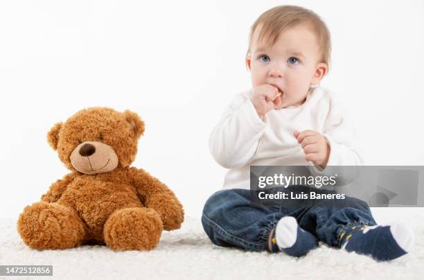 baby with fingers in the mouth with a teddy bear - ours en peluche photos et images de collection