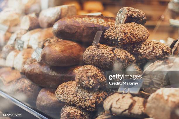 loaves of bread displayed in the window of a bakery. - bakery shelves stock pictures, royalty-free photos & images