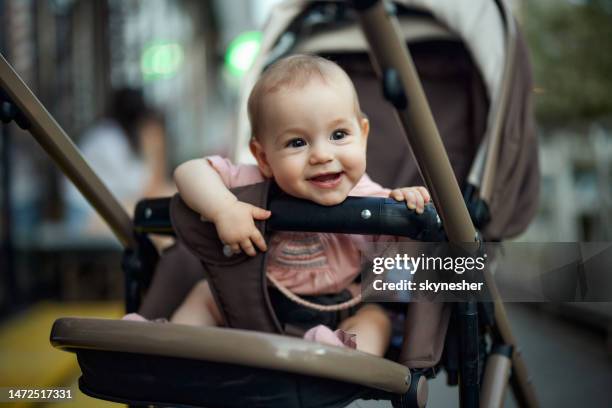 happy baby girl sitting in stroller outdoors. - kinderkoets stockfoto's en -beelden