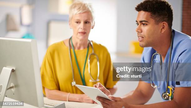 ward doctor and trainee discussing medical notes - junior doctor stock pictures, royalty-free photos & images