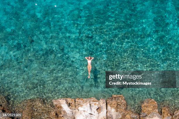 woman floating on turquoise sea, she enjoys her summer vacations, sun shining and clear water - croatia sea stock pictures, royalty-free photos & images