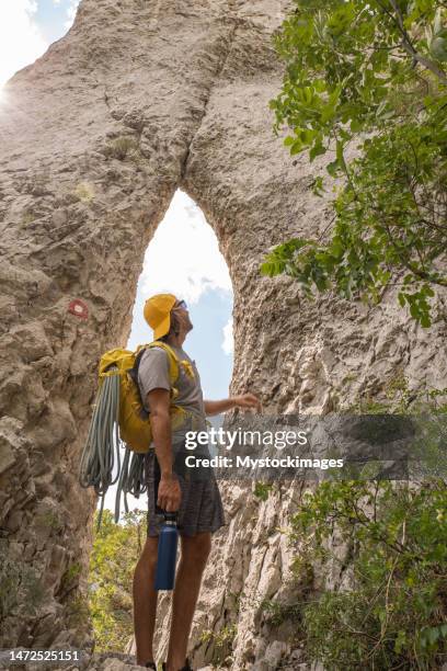 alpinista masculino mira las rocas pináculo y contempla la formación rocosa en la hermosa naturaleza - pinnacle rock formation fotografías e imágenes de stock