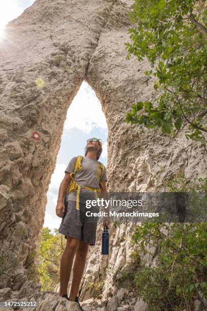 alpinista masculino mira las rocas pináculo y contempla la formación rocosa en la hermosa naturaleza - pinnacle rock formation fotografías e imágenes de stock