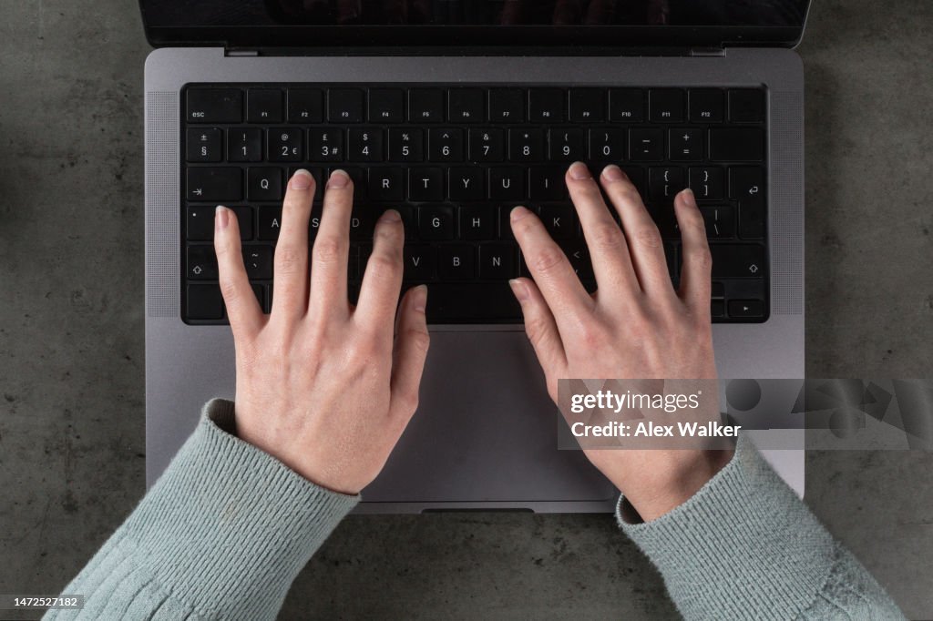 Top down personal perspective view of person working on modern laptop computer.