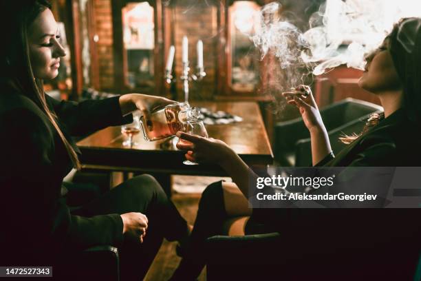 female pouring her friend another glass of scotch - flirting stock pictures, royalty-free photos & images