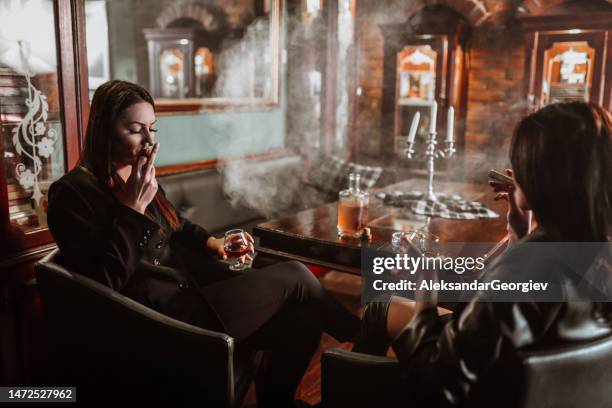 elegante geschäftsfrauen entspannen mit brandy und zigarren - cigar stock-fotos und bilder