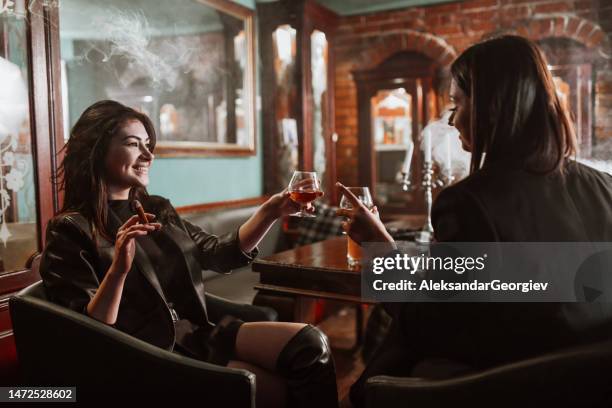 celebratory toast with whiskey and cigars by two beautiful females - whiskey stock pictures, royalty-free photos & images