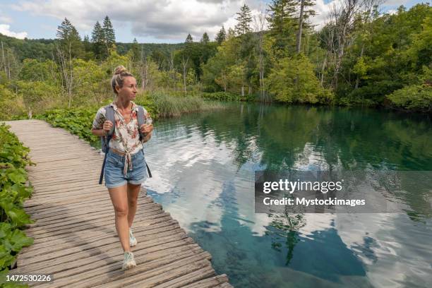 vorderansicht einer frau, die abenteuer in der natur erlebt und sich umsieht, seen und bäume - plitvice stock-fotos und bilder