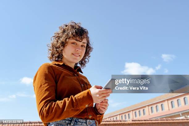 side portrait of caucasian woman student typing on phone outdoors on summer - studentin stock-fotos und bilder