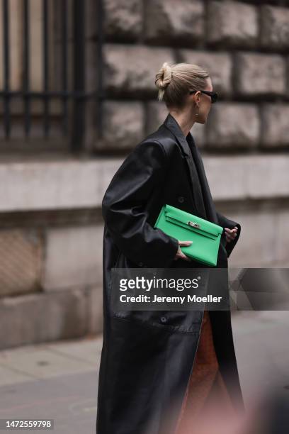 Leonie Hanne wears green Hermes bag, rust brown dress, black long leather coat and black sunglasses, outside Hermes during Paris Fashion Week -...