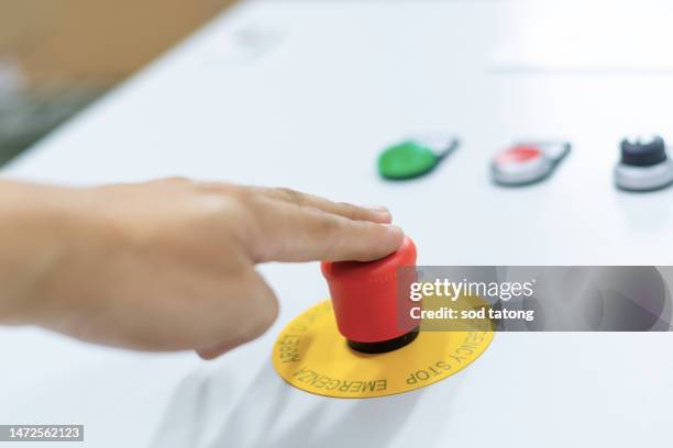 stop button and the hand of worker about to press it. emergency stop button. big red emergency button or stop button for manual pressing. - big red button stockfoto's en -beelden