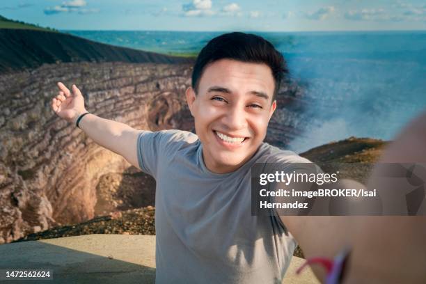 turista haciendose un selfie en un mirador. guapo turista tomando un selfie de vacaciones. hombre aventurero haciendose un selfie en un mirador. primer plano de la persona que toma un selfie de aventura. volcan masaya, nicaragua - primer plano stock-fotos und bilder