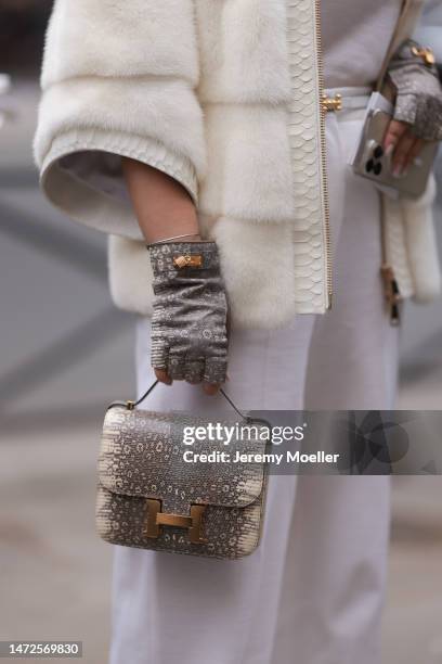 Fashion Week Guest seen wearing a white fur coat, white wide pants, Himalaya grey gloves and a Hermes Constance Himalaya handbag , outside Hermes...
