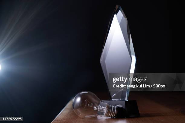 light bulb and crystal trophy on top of wooden table,malaysia - first light awards inside stock-fotos und bilder