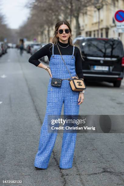 Paola Alberdi wears blue overall, black long sleeve shirt, black Chanel belt bag, beige bag with embroidered logo outside Chanel during Paris Fashion...