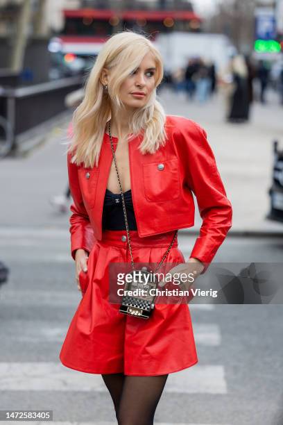 Xenia Adonts wears red varnished wide leg shorts, jacket, Chanel bag, black cut out top, tights outside Chanel during Paris Fashion Week - Womenswear...