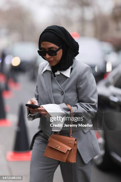 Fashion Week Guest seen wearing a grey suit, grey blazer, grey pants and white blouse, black sunglasses and a grey Hermes handbag, outside Hermes...