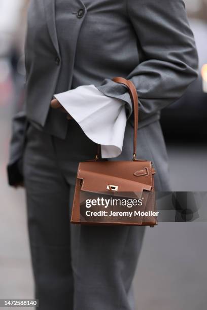 Fashion Week Guest seen wearing a grey suit, grey blazer, grey pants and white blouse, black sunglasses and a grey Hermes handbag, outside Hermes...