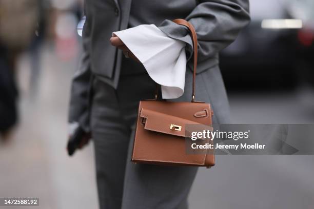 Fashion Week Guest seen wearing a grey suit, grey blazer, grey pants and white blouse, black sunglasses and a grey Hermes handbag, outside Hermes...