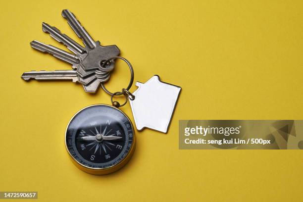 house key with compass key ring against yellow background,malaysia - key ring isolated stockfoto's en -beelden