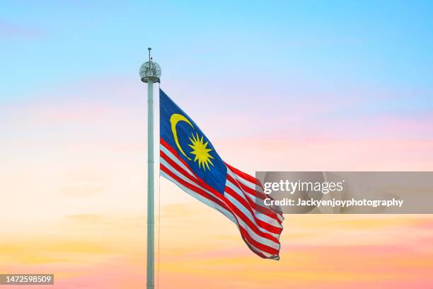 malaysia flag flying against twilight sky - malaysia flag stock pictures, royalty-free photos & images