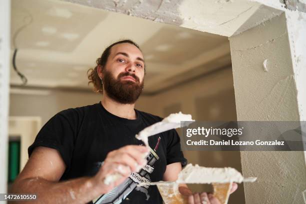 man looking at camera while repairing the walls of house - applying plaster stock pictures, royalty-free photos & images