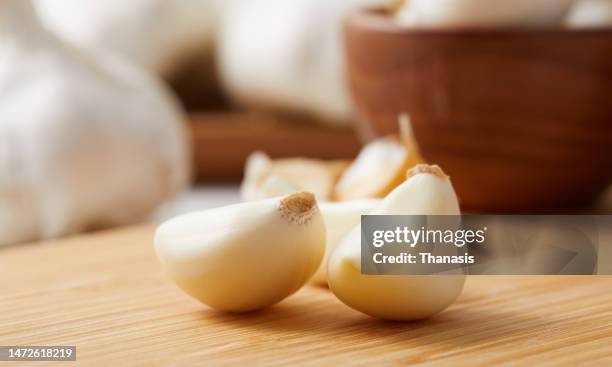 close up on a clove of garlic and garlic bulbs - garlic clove - fotografias e filmes do acervo