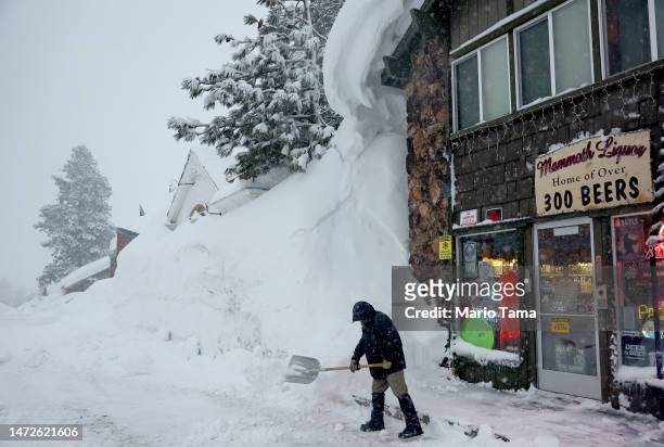 Spike Todd shovels in front of his store near snowbanks piled up from previous storms during another winter storm in the Sierra Nevada mountains on...