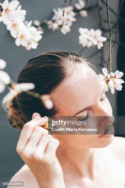 woman with pipette at spring flowers on background. - ayurveda stock pictures, royalty-free photos & images