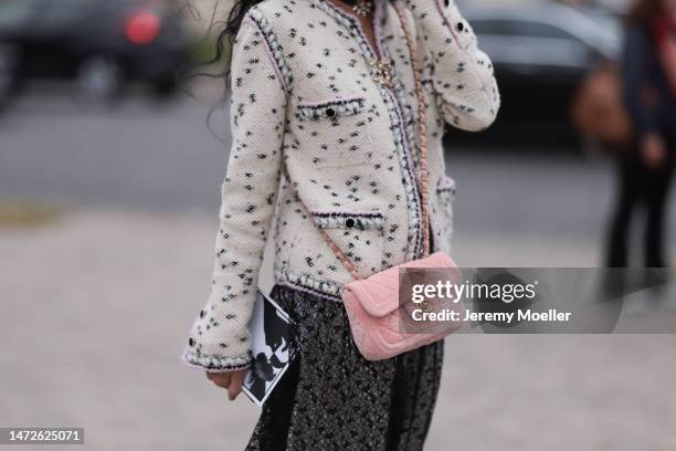 Fashion week guest seen wearing a white patterned blazer, a dark patterned skirt and a light pink bag before the Chanel show on March 07, 2023 in...