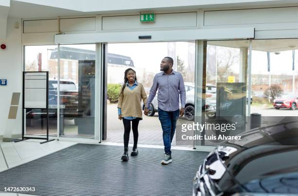 african couple visiting an automobile dealership to purchase a new car - sliding door stock pictures, royalty-free photos & images