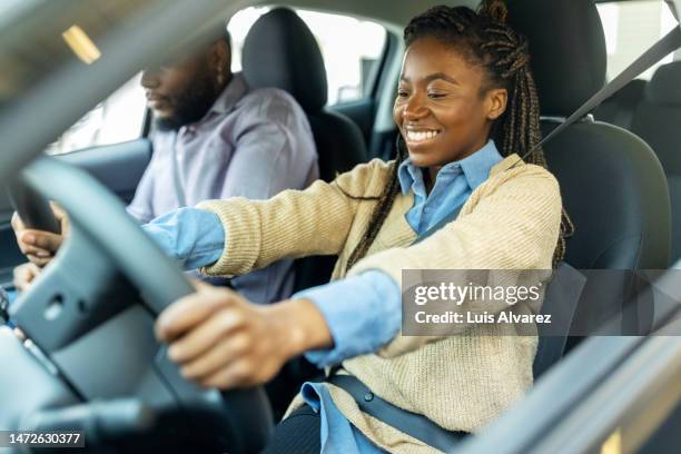 young couple sitting in new car and checking the comfort in a dealership - new jersey fotografías e imágenes de stock