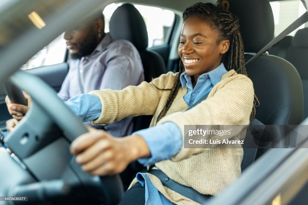 Young couple sitting in new car and checking the comfort in a dealership