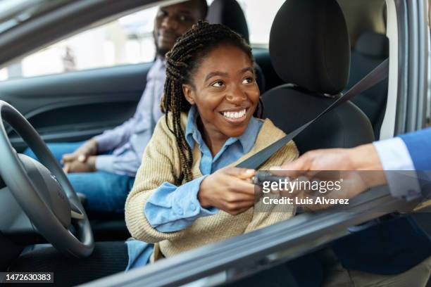 african couple getting car keys for test drive at showroom - dealer foto e immagini stock