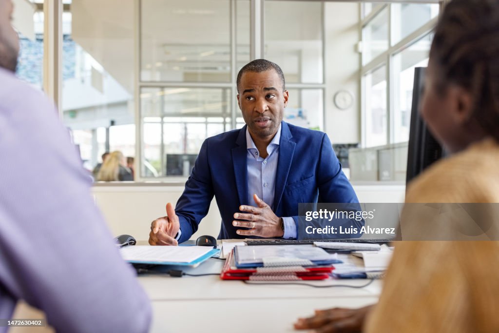 Auto dealer meeting with buyer couple in office