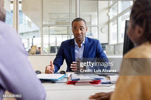 Auto dealer meeting with buyer couple in office