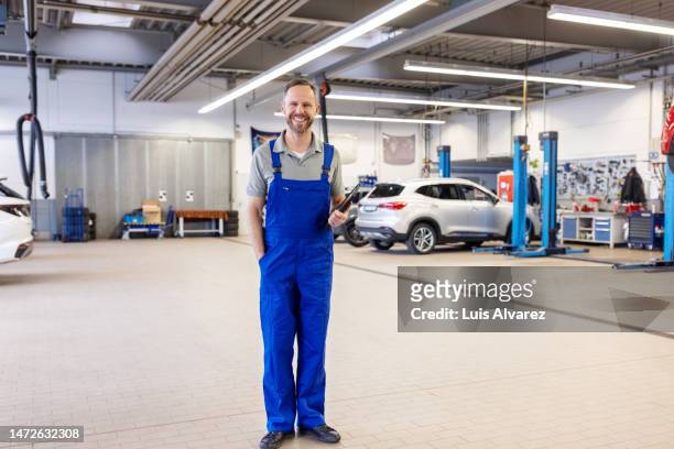 auto mechanic in uniform working at service station - hände in den taschen stock-fotos und bilder