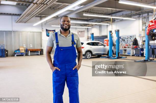 portrait of african man in uniform working at auto repair shop - tuinbroek stockfoto's en -beelden