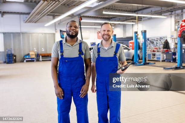 portrait of two mechanics standing together at a car workshop - overalls stock pictures, royalty-free photos & images