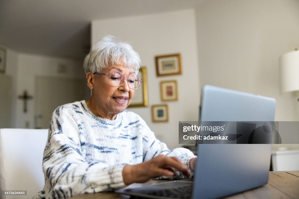 Seniorin mit einem Laptop zu Hause