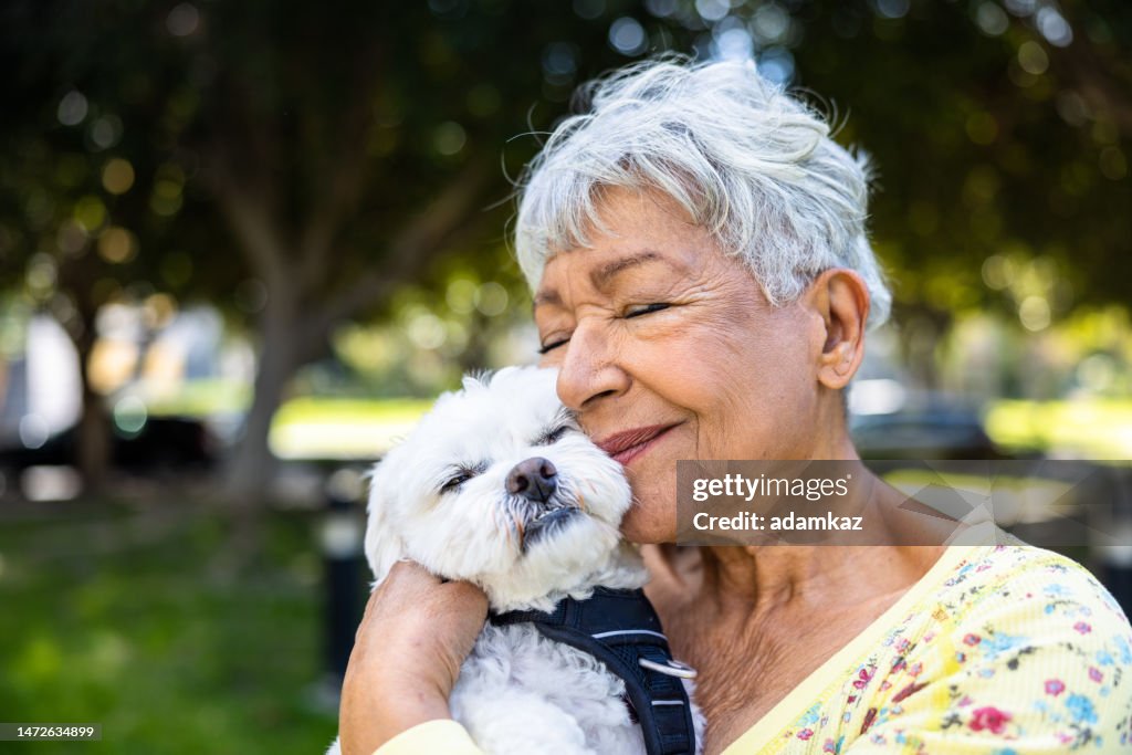 A mixed race senior woman holding her puppy outdoors