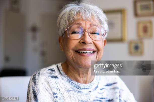 portrait of a beautiful mixed race senior woman in her home - old spectacles stock pictures, royalty-free photos & images