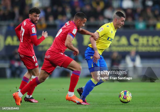 Sergi Guardiola of Cadiz CF battles for possession with Angel Algobia and Munir El Haddadi of Getafe CF during the LaLiga Santander match between...