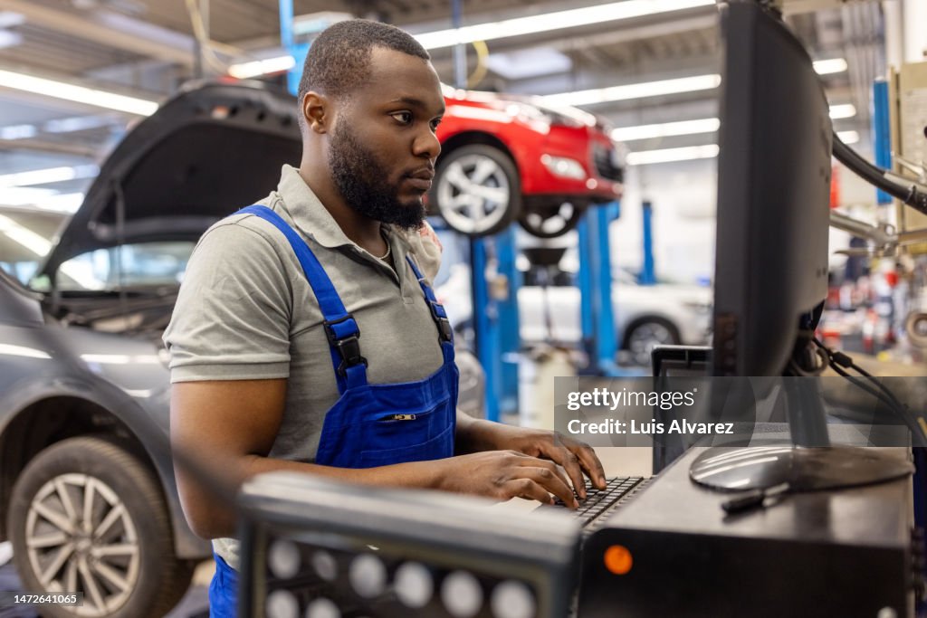 Mechanic Using A Computer African Mechanic Working On Computer At Wheel Alignment Station In ...